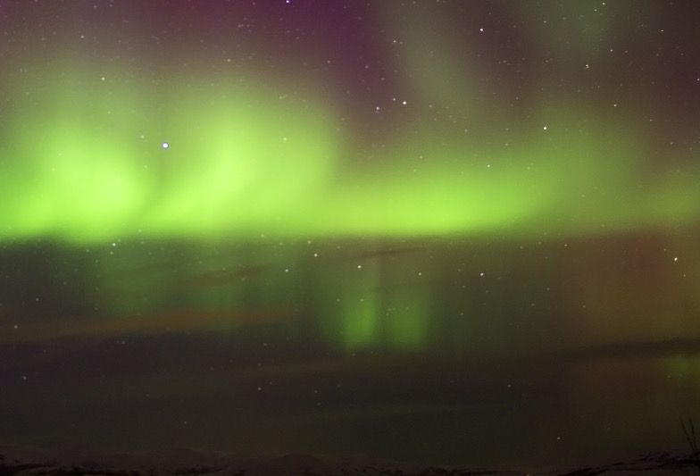aurora-glow Emerald curtains reflecting subtly off the snow and ice below.